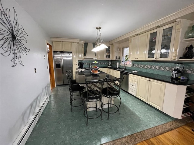 kitchen with sink, baseboard heating, tasteful backsplash, decorative light fixtures, and stainless steel appliances