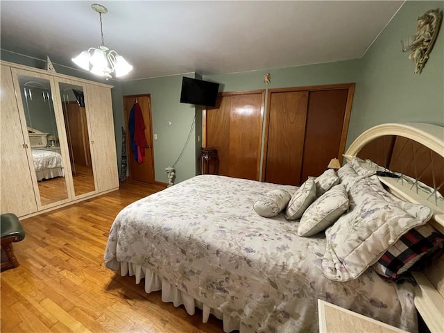 bedroom featuring a chandelier, wood-type flooring, and two closets