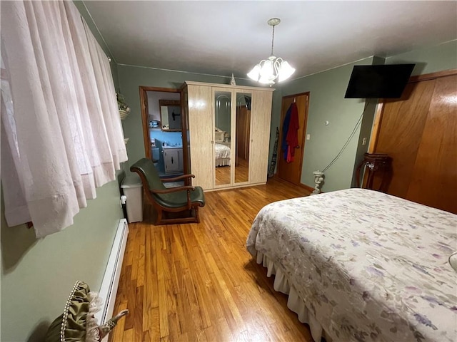 bedroom with an inviting chandelier, a baseboard radiator, and light hardwood / wood-style flooring