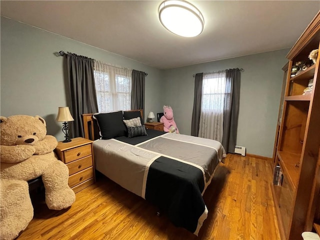 bedroom featuring baseboard heating, multiple windows, and light hardwood / wood-style flooring