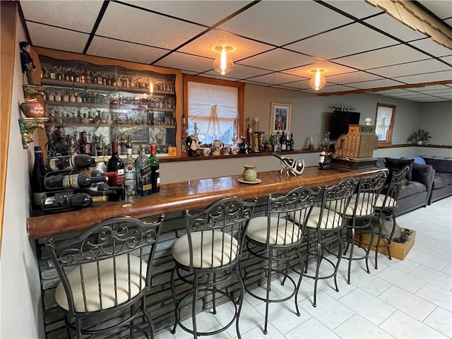 bar with a paneled ceiling and light tile patterned floors