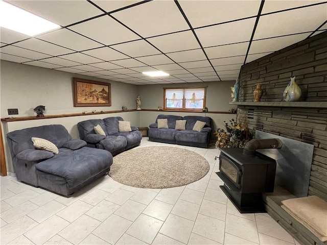 living room with light tile patterned floors, a paneled ceiling, and a wood stove