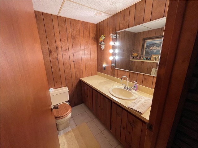 bathroom featuring wood walls, tile patterned flooring, vanity, and toilet