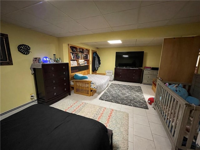 bedroom with light tile patterned floors, a paneled ceiling, and a baseboard heating unit