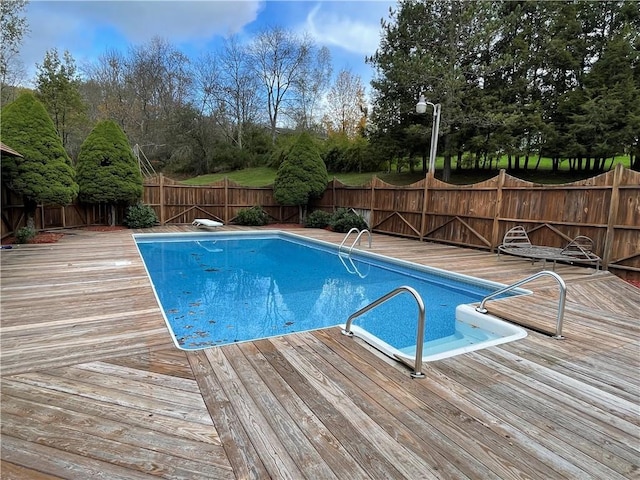 view of swimming pool with a wooden deck and a diving board