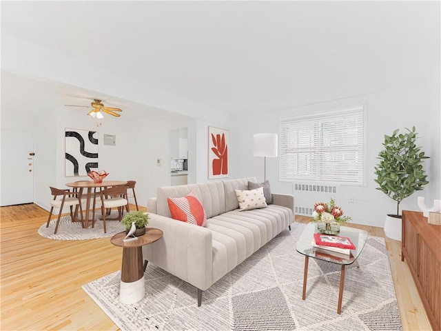 living room featuring ceiling fan, light hardwood / wood-style floors, and radiator