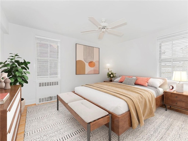 bedroom with ceiling fan, radiator heating unit, and light hardwood / wood-style flooring