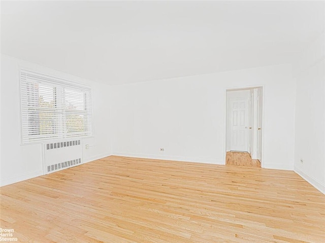 spare room featuring light hardwood / wood-style floors and radiator