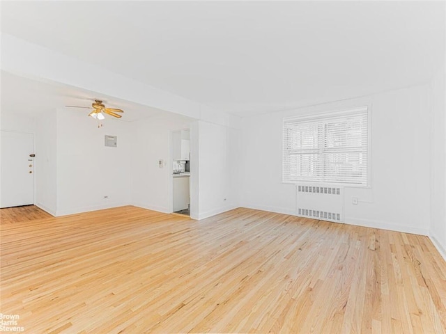 unfurnished living room featuring ceiling fan, radiator heating unit, and light hardwood / wood-style flooring