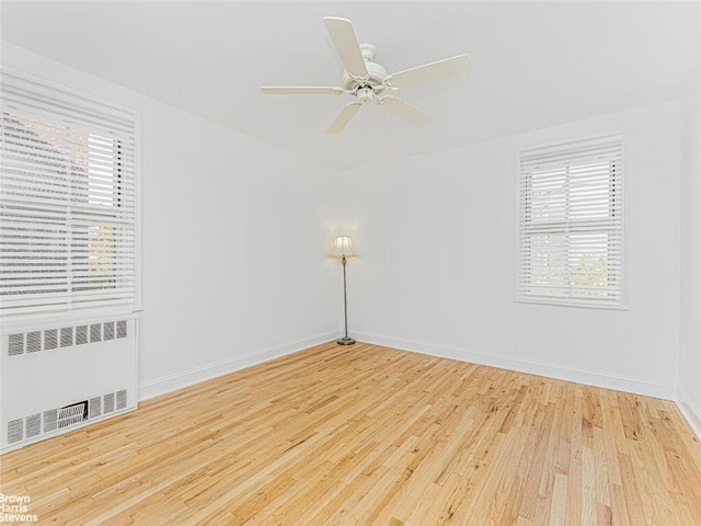 unfurnished room with ceiling fan, radiator heating unit, and light hardwood / wood-style floors