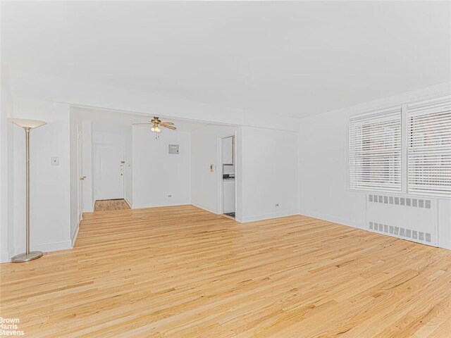 unfurnished room featuring ceiling fan, radiator, and light hardwood / wood-style flooring