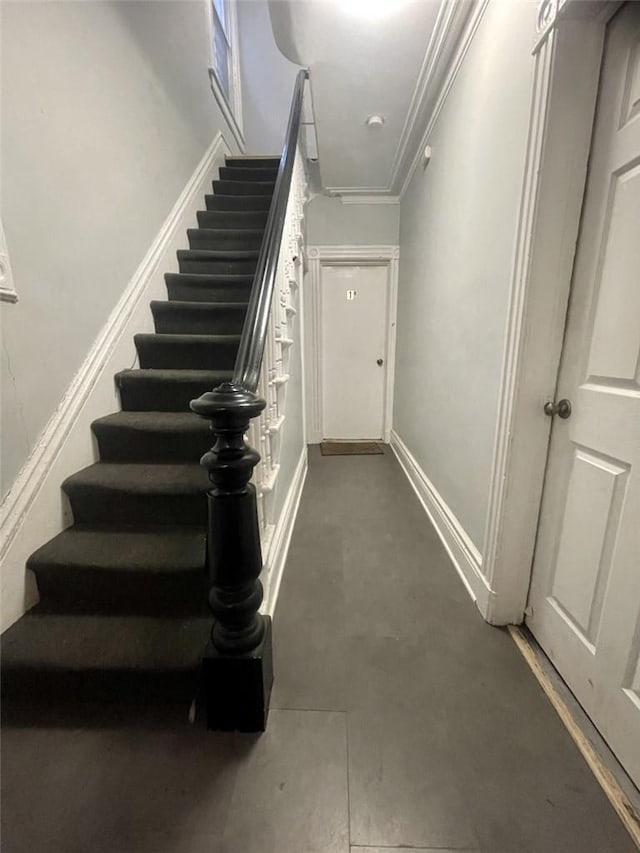 stairway featuring crown molding and concrete floors