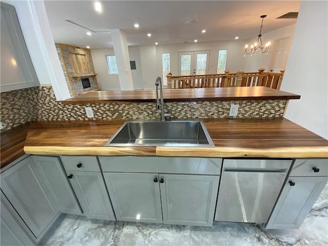 kitchen with backsplash, sink, a chandelier, butcher block countertops, and hanging light fixtures