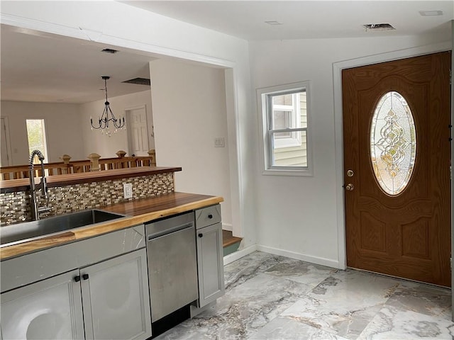 kitchen featuring gray cabinetry, sink, a notable chandelier, hanging light fixtures, and butcher block counters