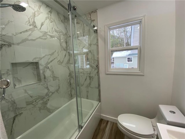 full bathroom featuring toilet, vanity, wood-type flooring, and combined bath / shower with glass door