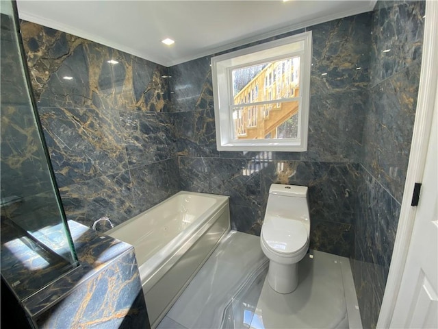 bathroom with a bathtub, toilet, ornamental molding, and tile walls