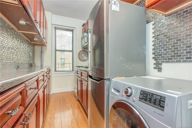 clothes washing area with washer / clothes dryer and light wood-type flooring