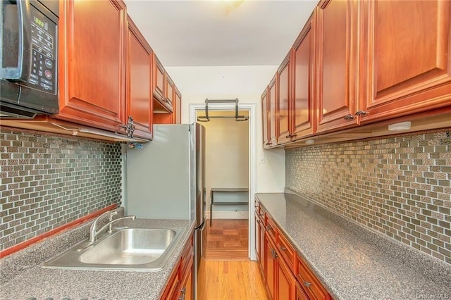 kitchen featuring stainless steel refrigerator, decorative backsplash, light hardwood / wood-style flooring, and sink