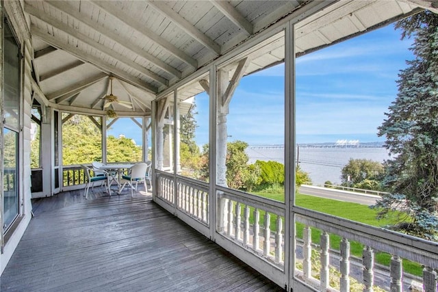 unfurnished sunroom with lofted ceiling with beams, ceiling fan, a water view, and wooden ceiling