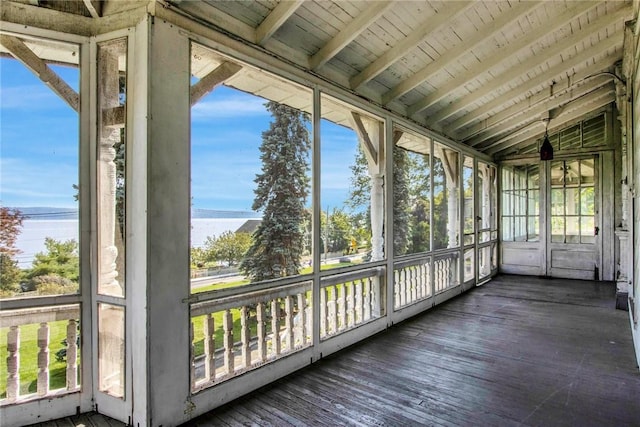 unfurnished sunroom featuring lofted ceiling with beams, a healthy amount of sunlight, a water view, and wooden ceiling