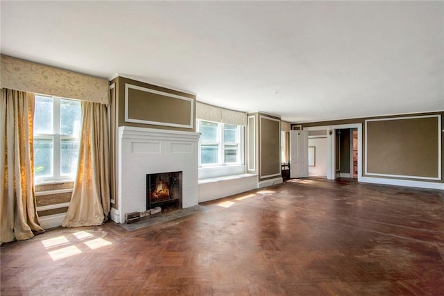 unfurnished living room featuring dark parquet floors and a brick fireplace