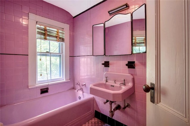 bathroom with a tub, sink, and tile walls