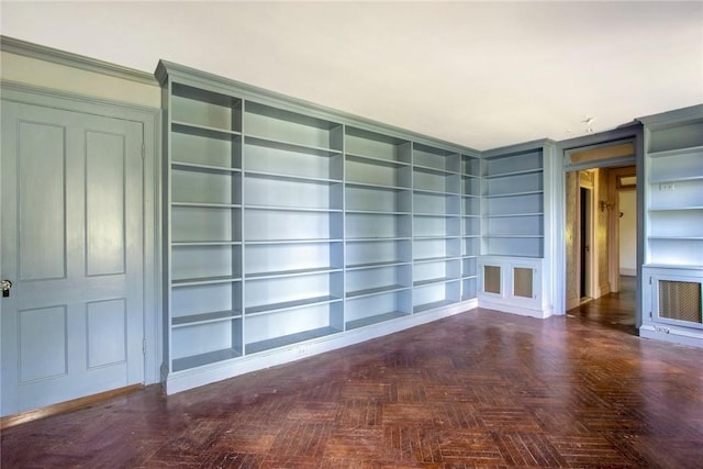 unfurnished living room featuring built in shelves and dark parquet flooring