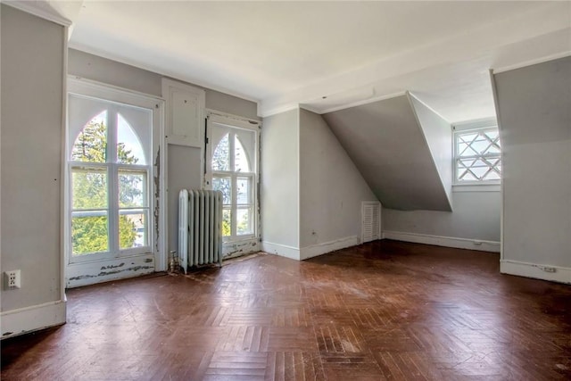 bonus room with dark parquet floors and radiator heating unit