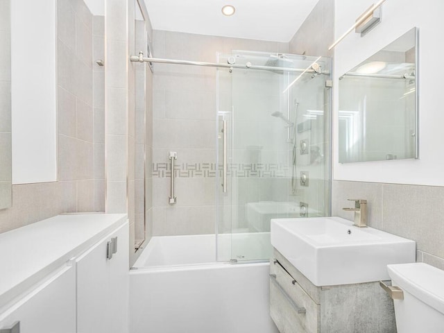 full bathroom featuring vanity, toilet, enclosed tub / shower combo, and tile walls