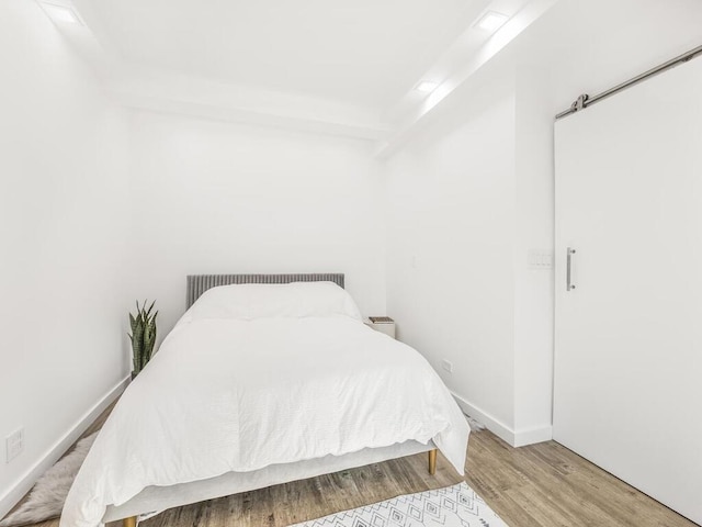 bedroom featuring beam ceiling and light wood-type flooring