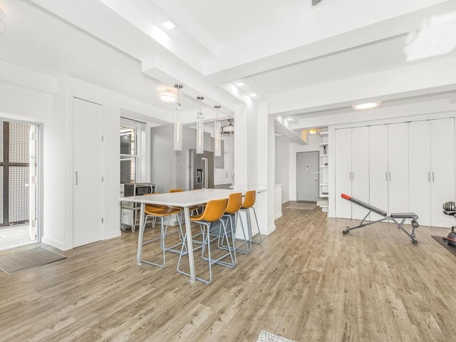 kitchen featuring a breakfast bar, pendant lighting, light wood-type flooring, and high end fridge