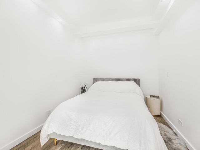 bedroom with hardwood / wood-style floors and beamed ceiling