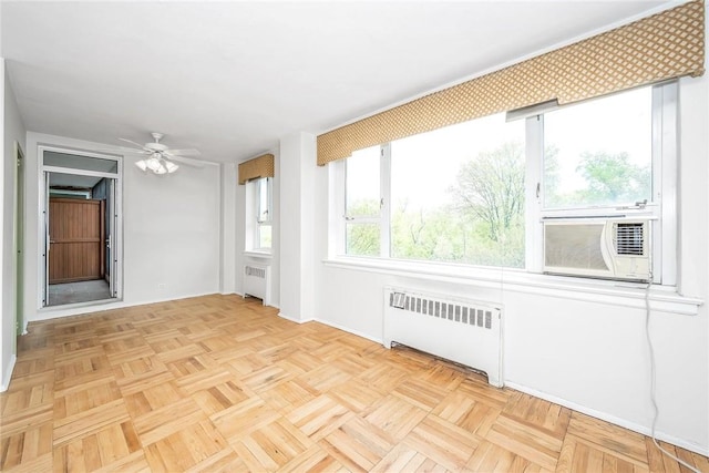 unfurnished sunroom with ceiling fan, radiator heating unit, and cooling unit