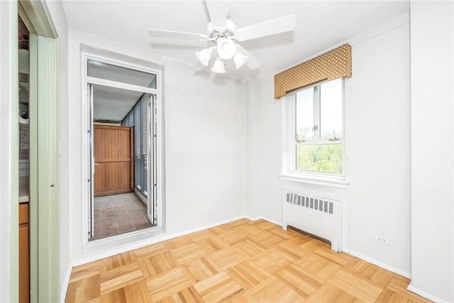 spare room with ceiling fan, parquet floors, and radiator