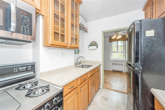 kitchen with radiator, light parquet floors, ceiling fan, sink, and black appliances