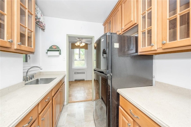 kitchen featuring radiator, ceiling fan, sink, black fridge, and light parquet floors