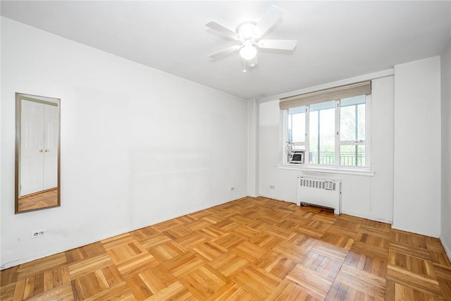 spare room featuring radiator heating unit, light parquet flooring, and ceiling fan