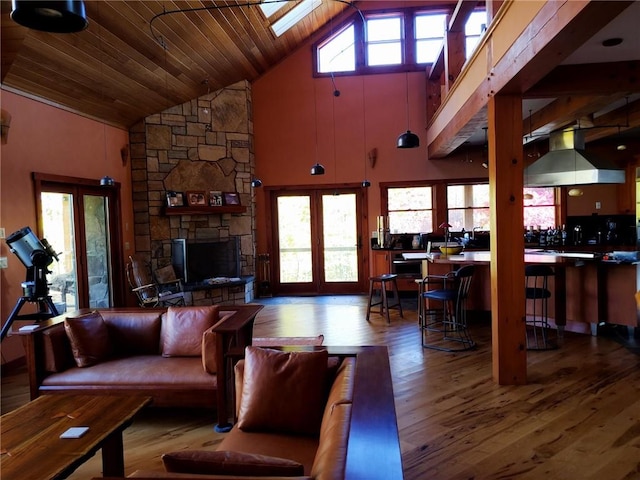 living room with hardwood / wood-style flooring, a healthy amount of sunlight, high vaulted ceiling, and a skylight