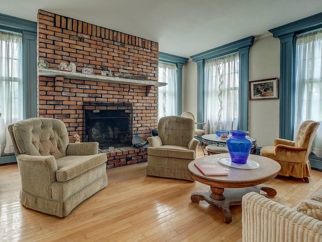 sitting room featuring ornamental molding, plenty of natural light, light hardwood / wood-style floors, and a brick fireplace