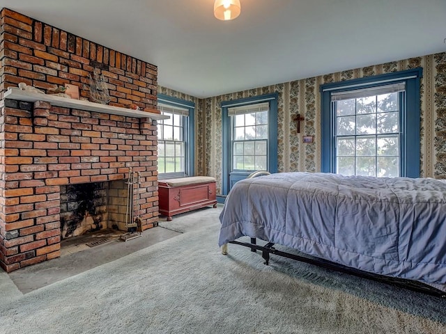 carpeted bedroom featuring a brick fireplace and multiple windows