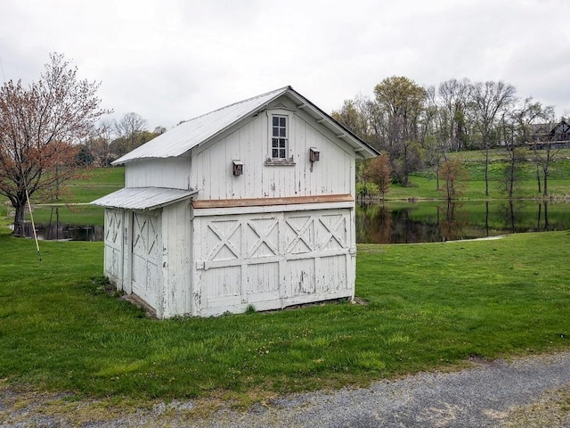 view of outdoor structure featuring a lawn and a water view