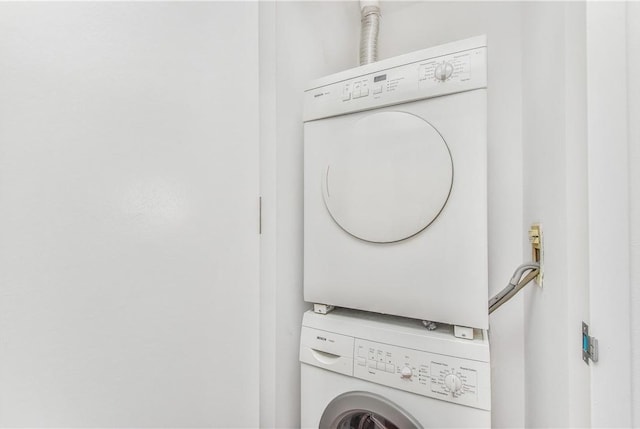 clothes washing area with stacked washing maching and dryer