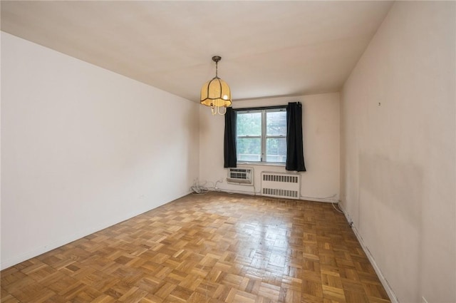 spare room with an AC wall unit, radiator heating unit, and parquet flooring