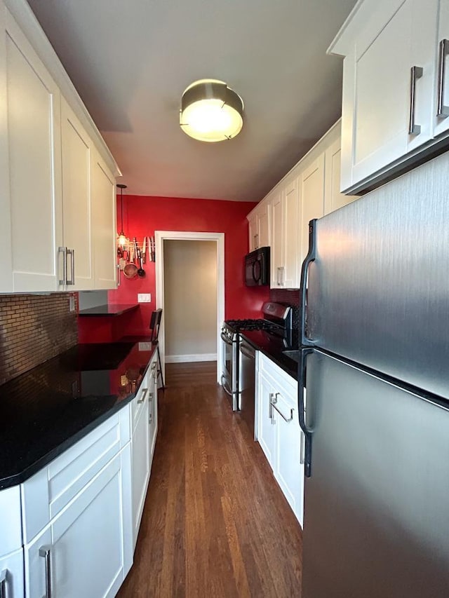 kitchen with backsplash, white cabinetry, dark wood-type flooring, and appliances with stainless steel finishes