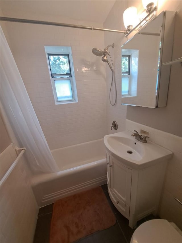 full bathroom featuring vanity, shower / bathtub combination with curtain, a healthy amount of sunlight, and tile walls