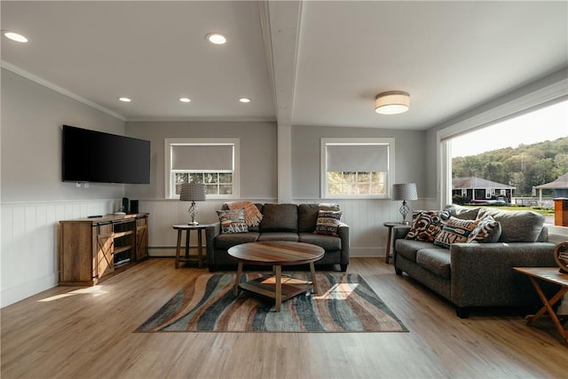 living room featuring beam ceiling, light wood-type flooring, a baseboard radiator, and ornamental molding