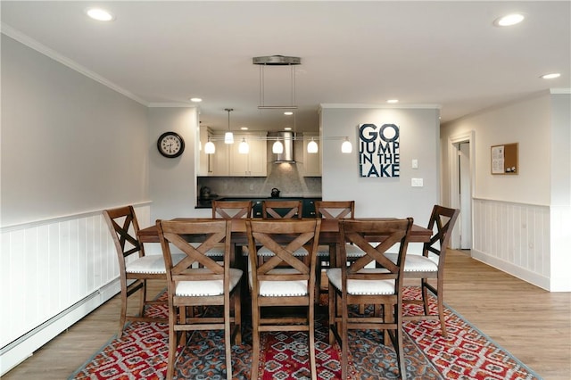 dining room featuring light wood-type flooring, baseboard heating, and ornamental molding