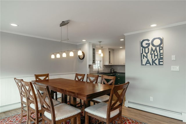 dining area featuring hardwood / wood-style floors, crown molding, sink, and a baseboard radiator