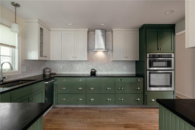 kitchen featuring white cabinetry, sink, wall chimney exhaust hood, green cabinets, and black stovetop