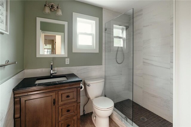 bathroom featuring vanity, tiled shower, hardwood / wood-style flooring, tile walls, and toilet